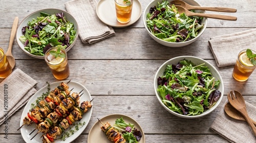 Grilled chicken skewers served with fresh mixed green salad and iced tea on a rustic wooden table