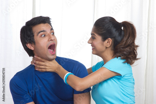 Cuadro en lienzo Playful young woman gripping man's neck at home