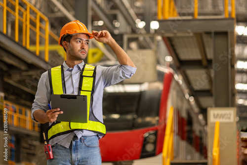 Electric train technician engineer with tablet checking controls system for security functions in maintenance infrastructure plant of sky train, public transportation vehicle, management concept.