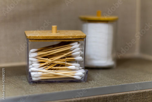 cotton swabs in storage container on bathroom shelf