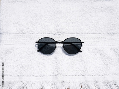Round Black Sunglasses on a White Textured Surface.