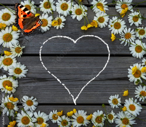 Herz aus Margeriten vor einer Holzwand