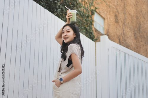 Young woman drinking iced coffee outside a chocolate shop