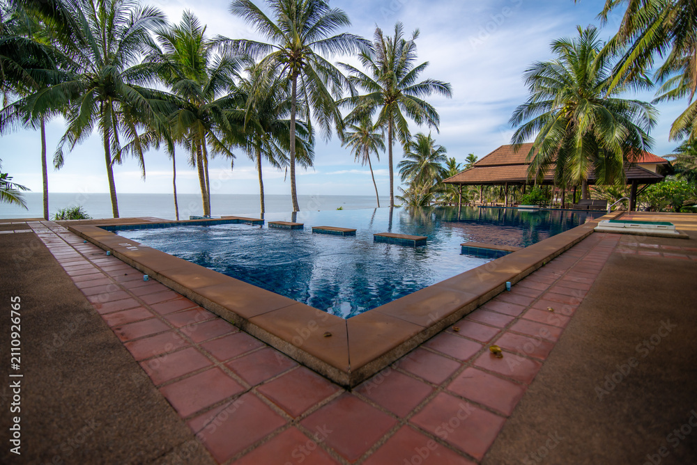 Fototapeta premium The swimming pool is located by the sea and is surrounded by coconut trees.