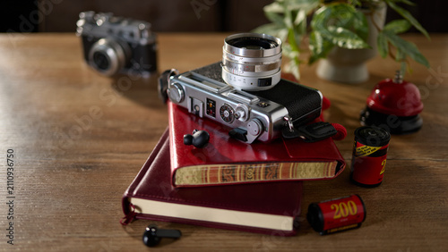 Bild auf Leinwand Old camera and notebooks are placed on a wooden table with a plant and film cani