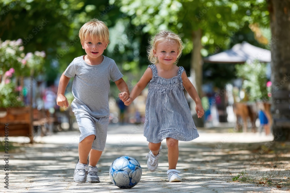 Obraz premium Two Toddlers Running with Soccer Ball Outdoors
