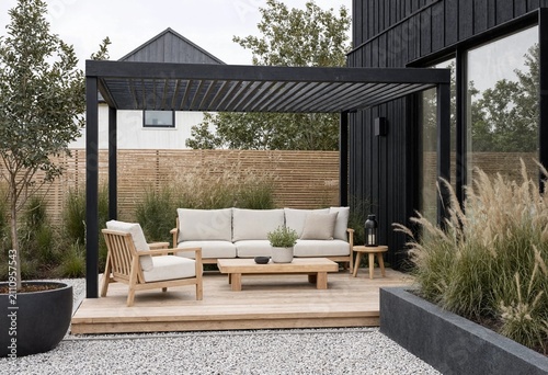 Elegant Scandinavian backyard featuring minimalist outdoor lounge, oak furniture, black pergola, ornamental grasses, gravel garden, modern residential landscaping, peaceful Nordic lifestyle, architect