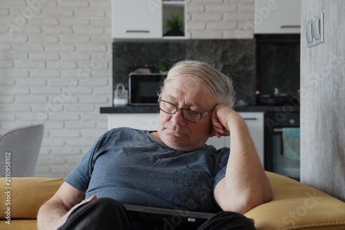 middle aged man asleep on sofa with laptop in kitchen