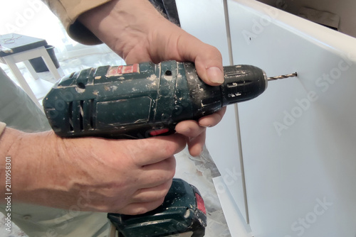 hand drilling white furniture panel with cordless drill