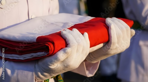 Gloved hands holding a folded Indonesian national flag.