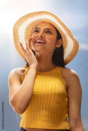 Fotografie A HAPPY YOUNG WOMAN APPLYING CREAM ON HER FACE ON A SUNNY DAY
