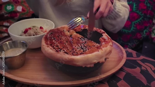 A warm pastry filled with rich flavors is carefully opened at a charming cafe. Tantalizing aromas fill the air as toppings are added, creating a delightful treat to savor.