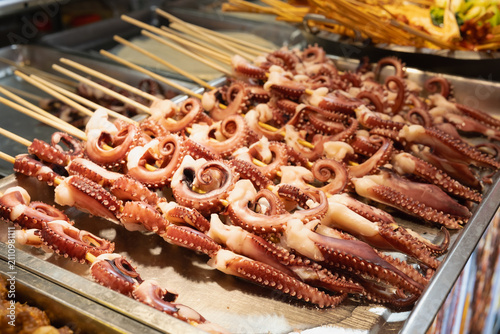 Fotografija grilled octopus tentacles on wooden skewers displayed at chinese street food market