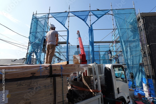 Construction Site with Mobile Crane Unloading Steel Beams and Siding Materials in Japan