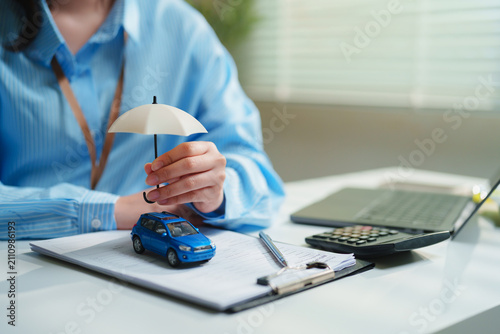 Принти на полотні Close-up Financial advisor holding an umbrella over a model car, vehicle insuran