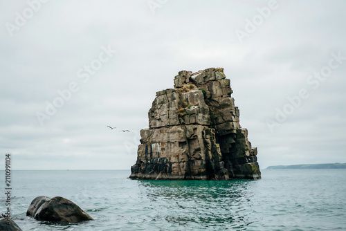 Large rock formation standing in the middle of the ocean illustration