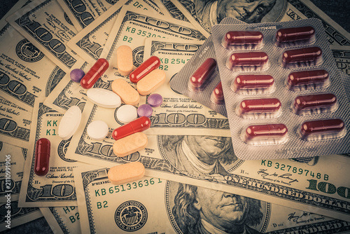 Pills and capsules on the background of dollar bills. Medicine concept