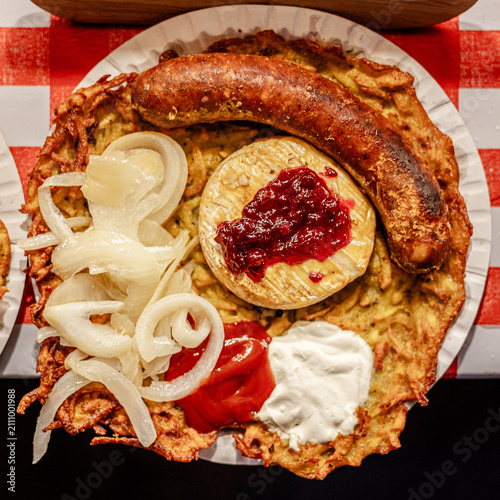 Potato pancake topped with sausage cheese onions ketchup and sour crea