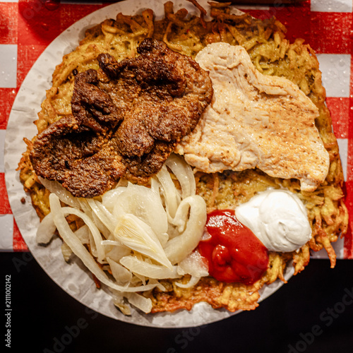 Hearty plate of hash browns fried meat onions ketchup and sour cream