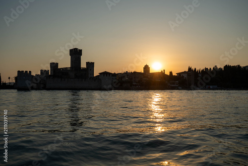 Sunset over Scaliger Castle in Sirmione view from boat on Lake Garda, Italy