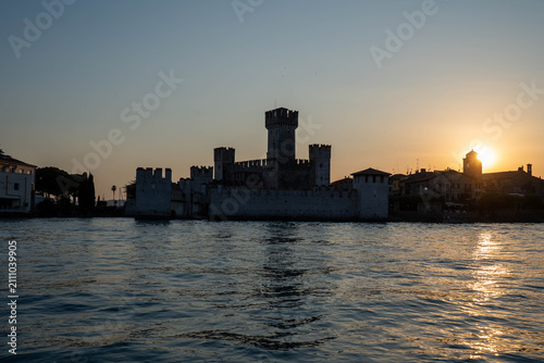 Sunset over Scaliger Castle in Sirmione view from boat on Lake Garda, Italy