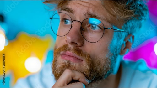 A thoughtful bearded man in glasses looks upward against a colorful financial chart background, symbolizing analysis, planning, creativity, and strategic decision-making