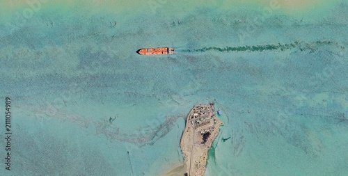 Fotografi Aerial view of an oil tanker passing a small resort island near Port Said Egypt across shallow turquoise Mediterranean waters