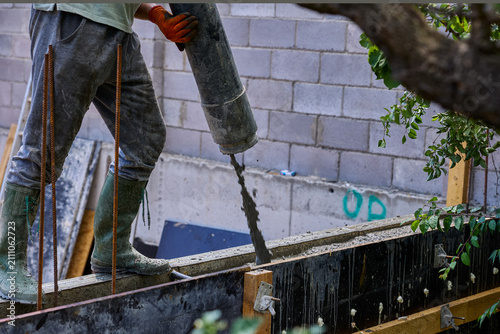 Construction Worker Pouring Concrete Into Foundation Formwork