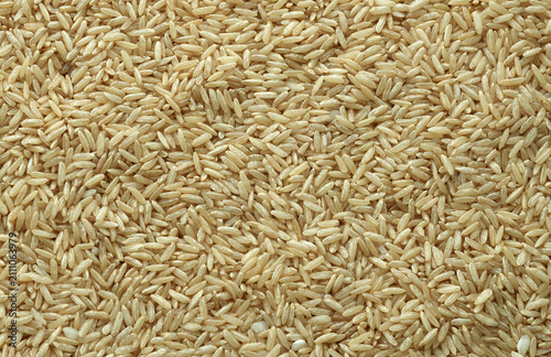 Dry brown rice grains in big pile on table close up. Large amount of brown rice seeds