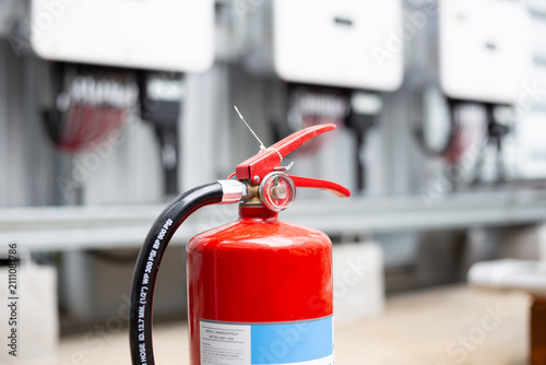 Red fire extinguisher installed on the solar cell fire extinguishing system control cabinet.