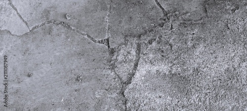 Monochrome cracked concrete floor texture with rough cement surface and weathered construction details. Black and white abstract background.