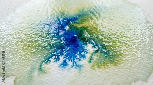 Vibrant blue and green watercolor ink bleeding on textured paper