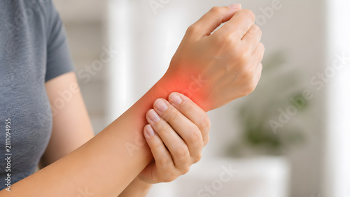 Woman holding painful wrist at home