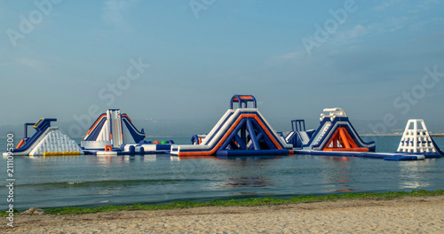 Colorful Inflatable floating water park with slides anchored in sea near beach