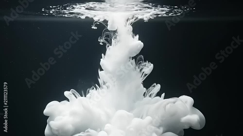 White Ink Cloud Spreading in Water on Black Background.