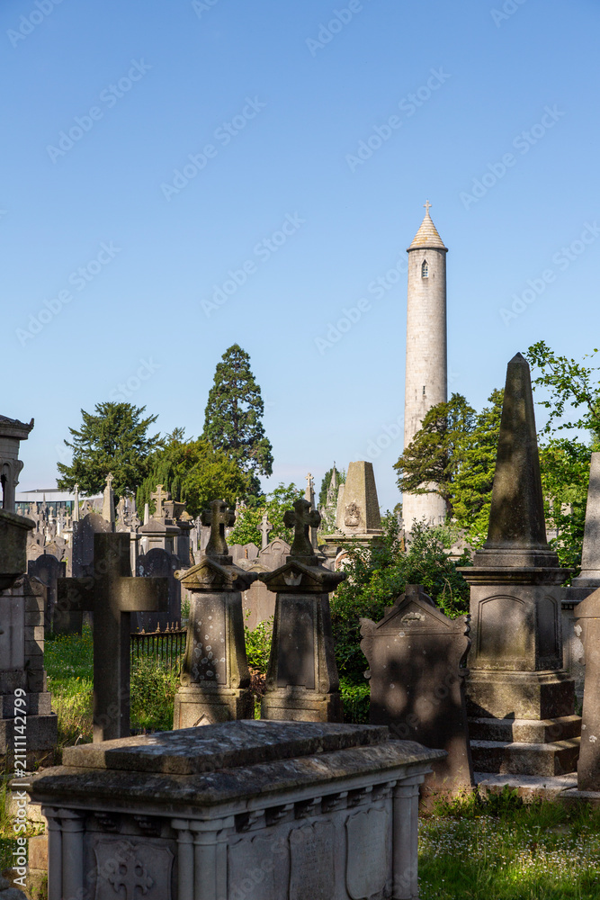 Fototapeta premium Monuments and trees, including the round tower commemorating Daniel O'Connell, Glasnevin Cemetery, Dublin, Ireland