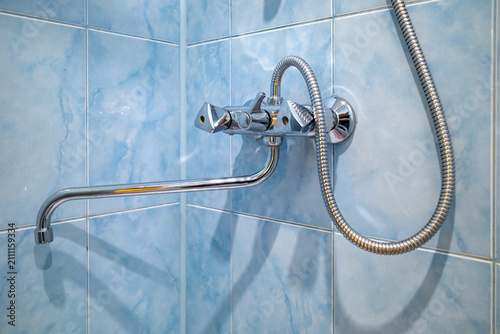 Modern chrome shower faucet on blue tiled wall