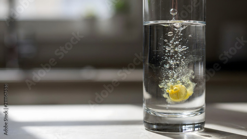 A yellow effervescent tablet dissolving in a tall glass of clear water