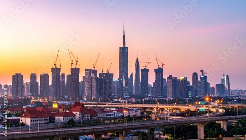 Modern City Skyline at Dusk with Construction Cranes and Illuminated Highways
