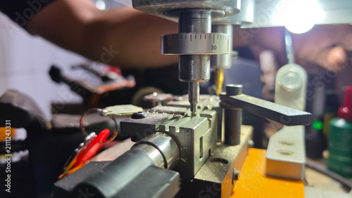 Fotografía Close-up of a locksmith duplicating an original metal key, precisely milling matching grooves into a new key blank with selective focus, highlighting professional security and replacement services