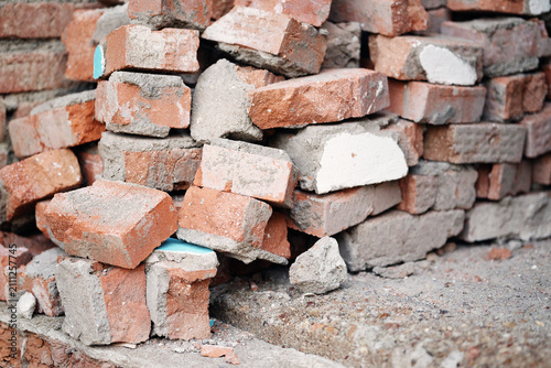 Obraz na płótnie A pile of old red bricks with traces of mortar stacked outdoors.