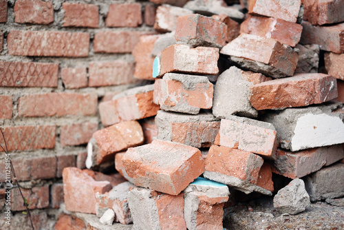 Fotografie A pile of old red bricks with traces of mortar stacked outdoors.
