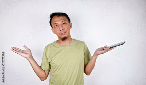 Konstfotografi Young Indonesian man making i dont know gesture in casual green clothes in white
