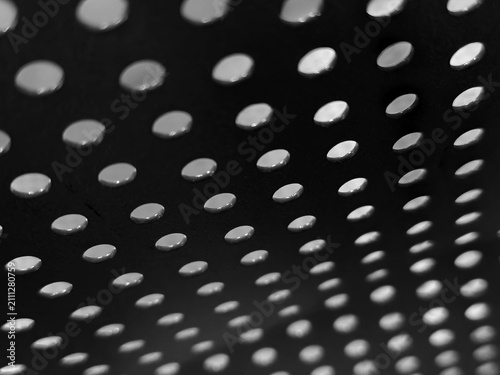 фотографія Perforated surface with repeating circular openings creates a pattern of light and shadow