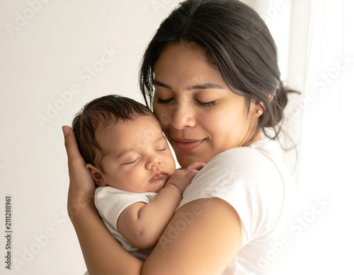 Mother holding her sleeping newborn baby close with love for world breastfeeding week celebration