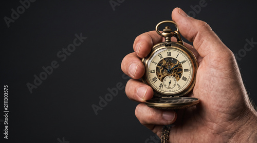 Hand holding antique pocket watch with intricate mechanical movement visible