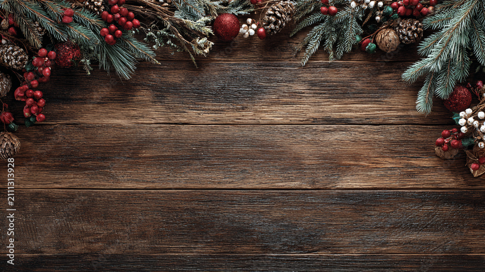 Obraz premium Festive Christmas background on dark wood featuring pine branches, cones, candy canes, red berries, angel wings, and gifts at top with copy space. 