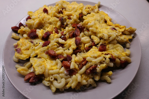 Plate with prepared food, pasta with pieces of sausage fried with egg
