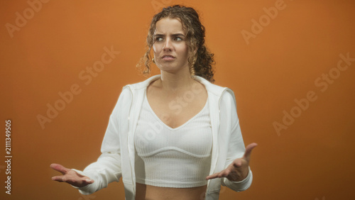 Canvastavla Young woman in white hoodie and crop top, open palms pleading and looking upward in studio; frustration yearning