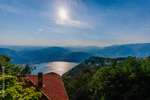Photography Scenic view of Lake Como surrounded by mountains and lush greenery under a clear